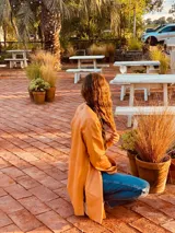 Tapado camel de cuero ovino con cuello clásico, cierre frontal con botones, bolsillos laterales y corte a la rodilla. Diseño slouchy y cómodo.