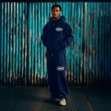 Pantalón de jogging azul marino con estampado gráfico blanco en la pierna derecha y logo circular en la pierna izquierda. Cuenta con cintura elástica y bolsillos laterales.