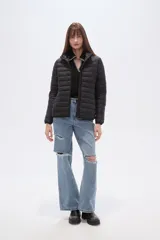 Campera acolchada tipo puffer, color beige claro, con capucha y cierre frontal. Presenta costuras horizontales y un calce entallado.