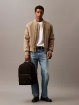 Mochila negra de poliéster reciclado con asa de mano y correas ajustables acolchadas. Tiene cierre principal con cremallera, bolsillo frontal con cremallera, bolsillos laterales expandibles y funda interior acolchada para portátil.