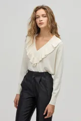 Sweater color crema de tejido de punto con lurex, escote en V con volados y mangas largas.