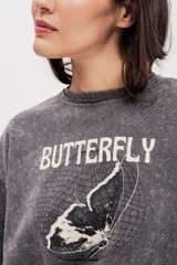 Buzo gris de felpa oversize con estampado frontal de mariposa y texto.