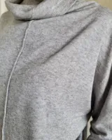 Polera gris oversize de lanilla, con cuello alto vuelto y costura central vertical en el frente. Manga larga y corte amplio.