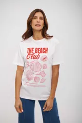 Remera blanca de manga corta con cuello redondo y estampado frontal en rojo que dice "THE BEACH Club" junto a ilustraciones de diferentes conchas marinas.