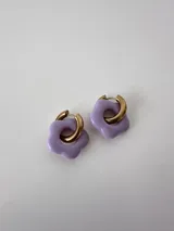 Aros de acero quirúrgico dorados con dije colgante en forma de flor de color lila.