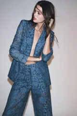 Blazer azul de encaje floral, con cuello solapa, manga larga con hombreras, falsos bolsillos delanteros y cierre frontal con un botón.