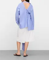 Camisa de algodón con diseño desestructurado a rayas celestes y blancas, cuello camisero, manga larga y cierre frontal de botones.