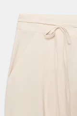 Pantalón de tiro alto color bordó, de corte ancho y pierna recta, con pinzas frontales y lazada ajustable en la cintura. El tejido presenta un acabado satinado o ligeramente arrugado.