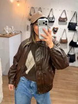 Campera de efecto cuero en color marrón chocolate, con diseño de corte relajado, cierre frontal, bolsillos amplios con solapa y terminaciones elastizadas en puños y ruedo.