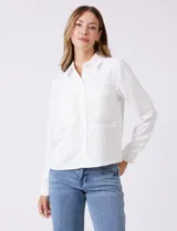 Camisa de crepe color beige con cuello clásico, cierre frontal con botones y dos bolsillos aplicados en el pecho.