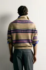 Sweater de punto jacquard de algodón y lino, color tostado con diseño de franjas geométricas en tonos violeta, fucsia y verde. Presenta cuello polo con cierre frontal de tres botones, mangas largas y puños y cintura en rib.