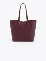 Cartera tipo shopper de cuero vacuno flor graneado, con formato amplio y estructura flexible. Presenta dos cierres verticales decorativos en el frente con tiracierres personalizados y doble manija de hombro.