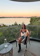 Blusa tipo lencera de satén color crema con escote en V y ruedo asimétrico, ambos decorados con encaje negro. Presenta breteles finos ajustables.