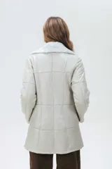 Campera de cuero tipo lambskin con diseño de paneles, cuello con solapas de piel sintética, cierre frontal con botones y bolsillos laterales.