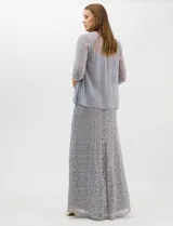 Vestido largo de encaje color beige, con escote recto decorado con pedrería y perlas, tirantes anchos y tajo lateral en la falda.