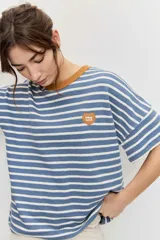 Remera de manga corta con diseño a rayas horizontales azules y blancas, cuello redondo en color tostado y parche bordado en el pecho.