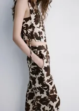 Pantalón largo de corte recto y tejido fluido, con diseño estampado floral en tonos marrón y crudo, bolsillos laterales y cierre oculto.