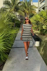 Vestido corto tejido a rayas horizontales en verde oscuro y beige, con cuello redondo y ribete celeste en el cuello y el dobladillo.