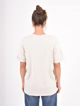Remera de algodón blanca, de corte holgado y manga corta con dobladillo.