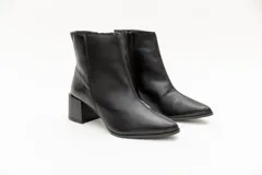 Bota de cuero negra, de caña corta y punta fina, con cierre lateral y taco geométrico de 6 cm.