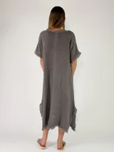 Vestido largo holgado color gris, con mangas cortas, escote en V y detalles de flecos en los bordes y aberturas laterales.