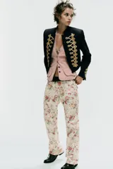 Jeans rectos de tiro medio con estampado floral multicolor sobre base blanca, trabillas para cinto, bolsillos delanteros y cierre frontal con cremallera y botón metálico.