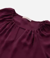 Blusa tipo bata de crepé color bordó, con cuello redondo, detalle de escote en V y mangas 3/4 con fruncidos.