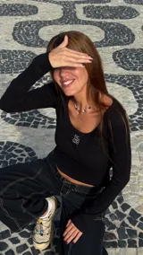 Top de manga larga color negro, confeccionado en tejido acanalado, con escote redondo y detalle de logo bordado en el centro del pecho.