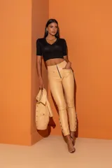 Pantalón de cuero sintético color beige, con cintura elástica, cierre frontal con cremallera y botones decorativos en los tobillos.