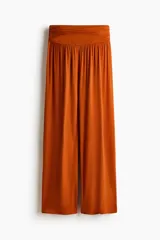 Pantalón wide leg de corte holgado en punto elástico de viscosa color naranja, con cintura elástica ancha y frunces laterales.