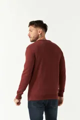 Sweater de punto color negro con escote en V, manga larga y puños acanalados. Presenta un pequeño logo bordado en el pecho.
