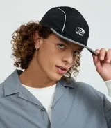 Gorra negra de microfibra, modelo 5 panel, con visera plana y logo estampado en blanco.
