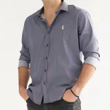 Camisa de hombre de algodón a rayas verticales azul marino y blancas, con cuello italiano, manga larga y cierre con botones. Presenta un pequeño logo bordado en el pecho.