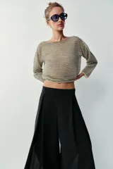 Pantalón fluido de tiro alto en color blanco, con pinzas delanteras, cintura elástica en la espalda y perneras anchas con aberturas laterales pronunciadas.