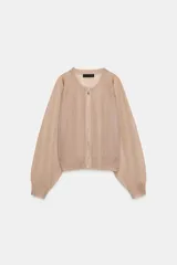 Chaqueta estilo bomber de punto color beige con acabado brillante, cuello redondo, manga larga con puños elásticos y cierre frontal con cremallera.