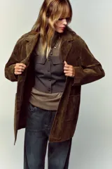 Top bustier corsetero color gris oscuro, con escote recto, solapa y hombros descubiertos. Presenta falsos botones forrados a tono en el frente y cierre lateral con cremallera oculta.