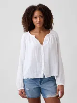 Camisa de muselina blanca, con escote en V fruncido y mangas largas holgadas.