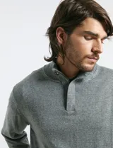 Sweater de punto color tostado, con cuello alto y cierre frontal parcial con botones. Diseño de manga larga con puños y ruedo acanalados.