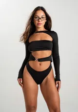 Body de manga larga color negro con diseño cut-out en el pecho y abdomen, con detalle de argollas metálicas plateadas en el centro.