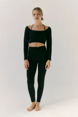 Top deportivo negro de manga larga, tejido de morley sin costuras. Presenta escote cuadrado y tiras finas cruzadas en la espalda.