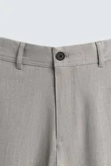 Pantalón chino de corte slim fit, confeccionado en tejido elástico. Presenta bolsillos frontales, bolsillos traseros de vivo con botón y cierre frontal con cremallera y botón.