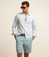 Bermuda masculina de sarga en color blanco, con cierre frontal de botón y cremallera, trabillas para cinturón y bolsillos laterales.