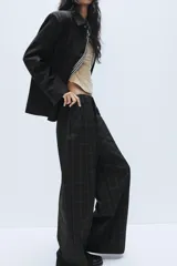Pantalón de tiro alto con diseño a cuadros, pernera recta y trabillas para cinturón. Cuenta con bolsillos laterales y cierre frontal con cremallera, botón oculto y gancho metálico.