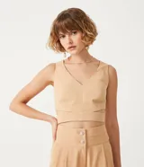 Blusa corta color beige con escote en pico y tirantes anchos. Presenta un recorte en la cintura.