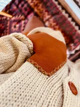 Cardigan de lana color crudo con bolsillos de cuero color marrón y botones de madera.