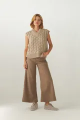 Chaleco de punto color beige con diseño trenzado, escote en V y sin mangas.