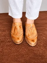 Zapatos de cuero color tostado con diseño calado en el empeine, talón abierto, pulsera regulable con hebilla lateral y taco bajo efecto madera.