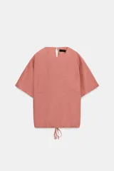 Top de lino color rosado, con cuello redondo, manga corta y bolsillos frontales plaqué. Cuenta con bajo ajustable mediante cordones y cierre en la espalda con abertura y botón.