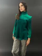 Buzo verde esmeralda de lana merino con cuello alto y mangas largas. Presenta dos texturas: afieltrada en cuello, mangas y ruedo, y tejido merino superfino en el delantero y la espalda.