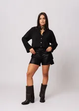 Short negro de tiro alto confeccionado en gabardina stretch metalizada, con bolsillos laterales y cierre frontal con cremallera y botón.